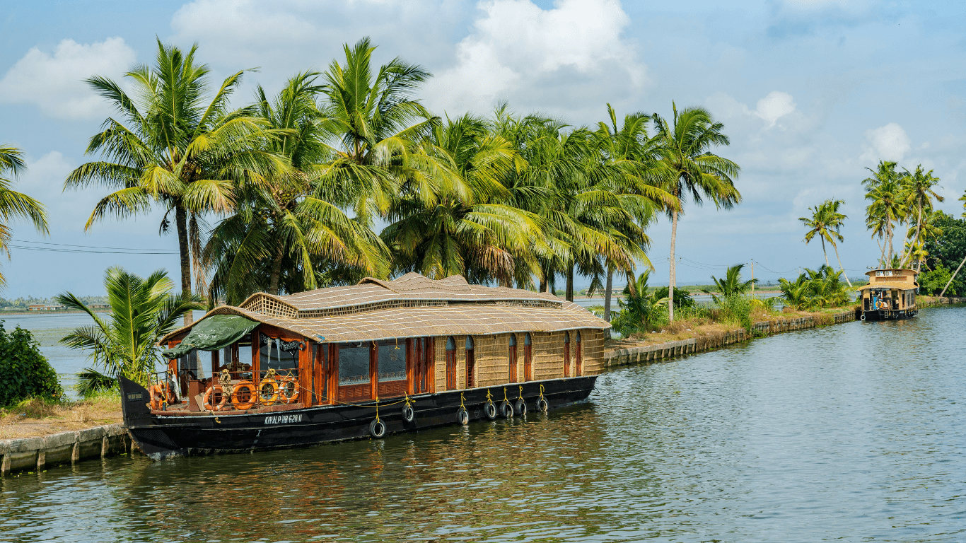 Long shot of Alleppey houseboat reflecting in still backwater amidst coconut trees give best Kerala tour Package experience