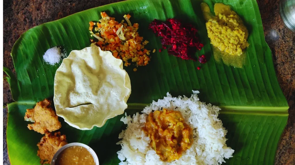 A traditional Kerala feast called Onam Sadhya, featuring a colorful array of vegetarian dishes like sambar, avial, thoran, and payasam served on a green banana leaf, a culinary highlight of Kerala Food Guide